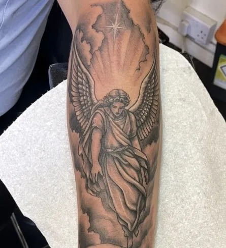 Black and grey guardian angel tattoo with rays of light and clouds on the forearm by Ivan Todorov at N9 Tattoo, Edmonton, North London