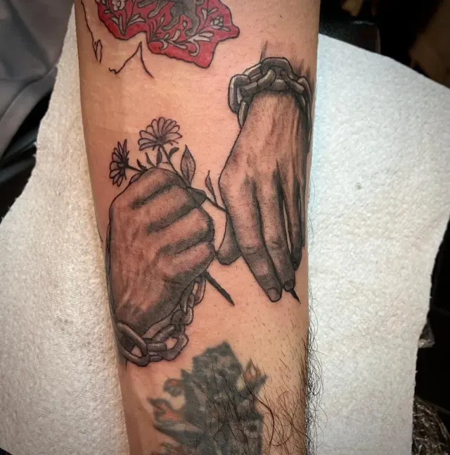 Black and grey realism tattoo of shackled hands with flowers, N9 Tattoo, Edmonton, North London